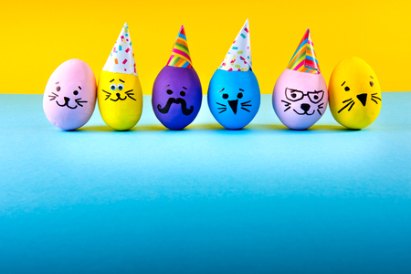 Funny handmade eggs on blue and yellow background. Easter holiday.の写真素材