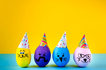 Funny handmade eggs on blue and yellow background. Easter holiday.の写真素材