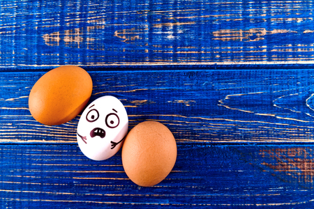 Funny easter eggs with scared face on blue wooden background.の写真素材