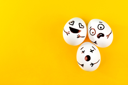 Easter eggs with different funny faces on yellow background. Top view.の写真素材