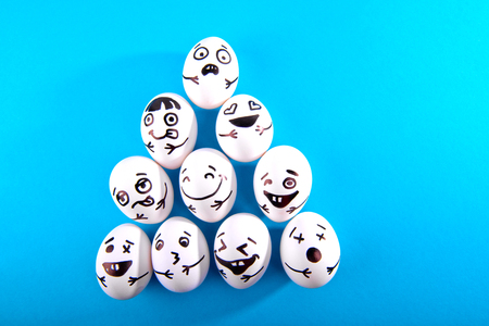 Easter eggs with different funny faces on blue background with copy space. Top view.の写真素材