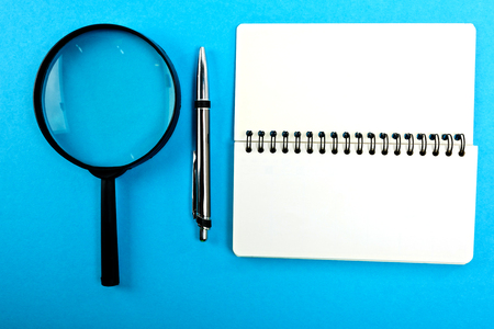 Magnifying glass with empty blank and pen on blue table.の写真素材