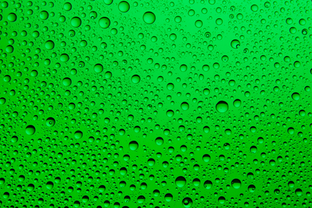 Green water drops on glass background.の写真素材