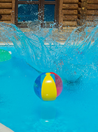 A colored inflatable ball in the pool with splashes.の写真素材