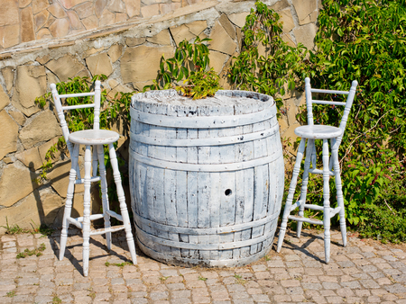 A barrel in the form of a table is painted white and two chairs. Concept of a street cafe.の写真素材