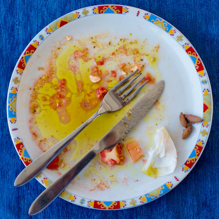 Dirty round plate after eating against a blue napkin. Top view.の写真素材