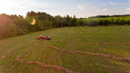 Aerial view of tractor collects hay from the field.の写真素材