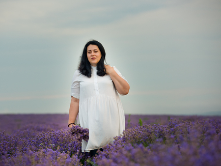 Young girl in white dress, posing in a lavender field.の写真素材