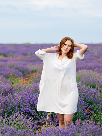 Young girl in white dress, posing in a lavender field.の写真素材
