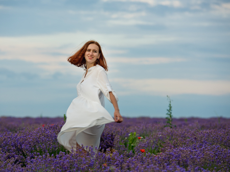 Young girl in white dress, posing in a lavender field.の写真素材
