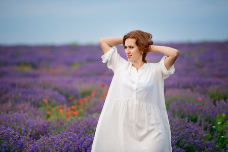 Young girl in white dress, posing in a lavender field.の写真素材
