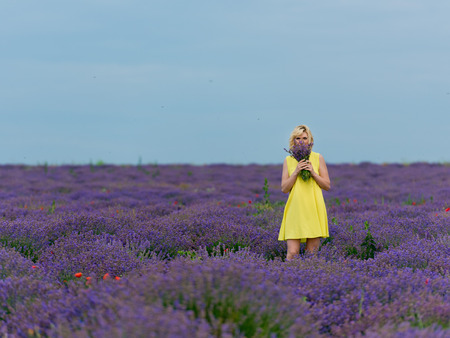 Young girl in yellow dress, posing in a lavender field.の写真素材