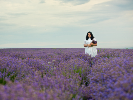 Young girl in white dress, posing in a lavender field.の写真素材