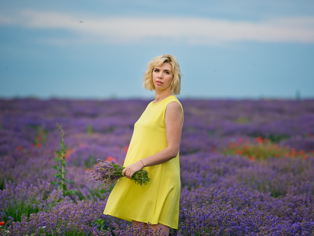 Young girl in yellow dress, posing in a lavender field.の写真素材