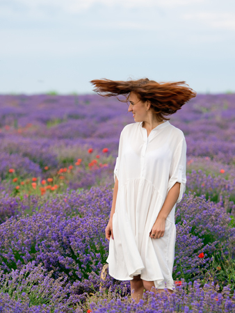 Young girl in white dress, posing in a lavender field.の写真素材
