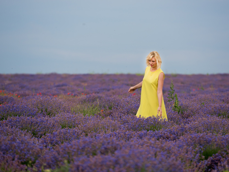 Young girl in yellow dress, posing in a lavender field.の写真素材
