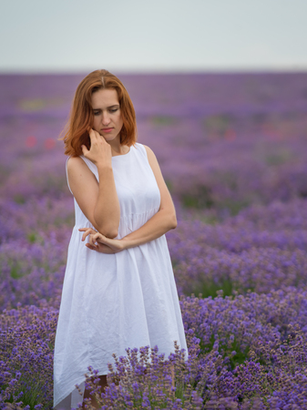 Young girl in white dress, posing in a lavender field.の写真素材