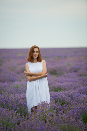 Young girl in white dress, posing in a lavender field.の写真素材