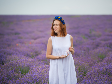 Young girl in white dress, posing in a lavender field.の写真素材