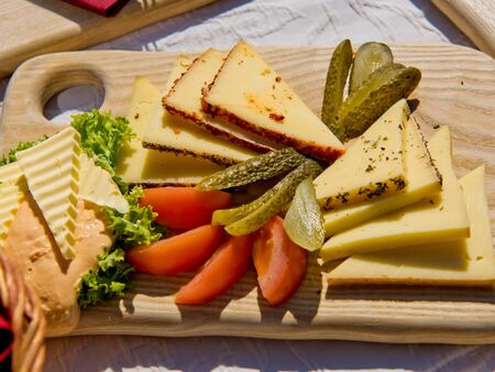 Cheese and vegetable slices on a wooden board.の写真素材