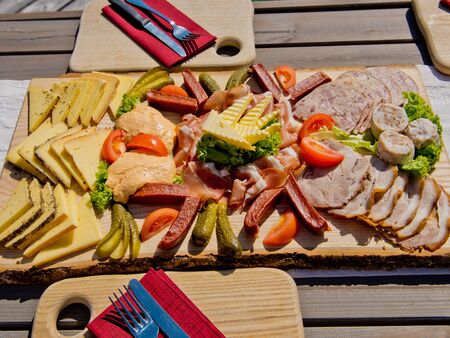 Cheese, meat and vegetable slices on a wooden board.の写真素材