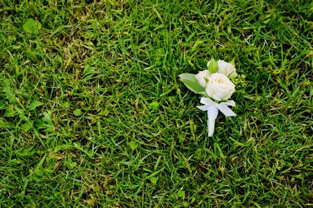 Groom's boutonniere on a green grass in the park.