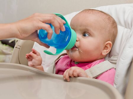 Baby drinks water from a bottle.の写真素材