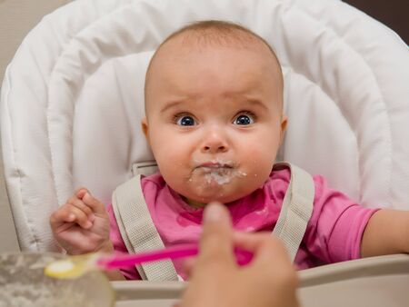 Mother feeding her baby girl with a spoon.の写真素材