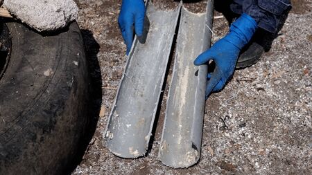 A plumber in rubber gloves cut a plastic sewer pipe lengthwise into two halves.の写真素材