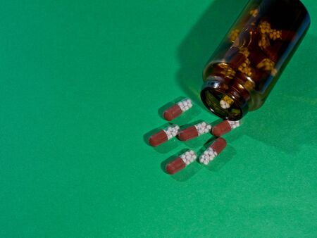 Pharmaceutical capsules and glass bottle on green background.の写真素材