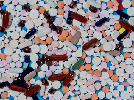 Assorted pharmaceutical medicine pills, tablets and capsules over blue background.の写真素材