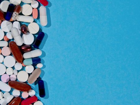 Group of pharmaceutical medicine pills, tablets and capsules on a blue background with copyspace.の写真素材