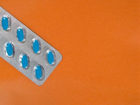 Blue pills in a blister pack on an orange background with copy space.の写真素材