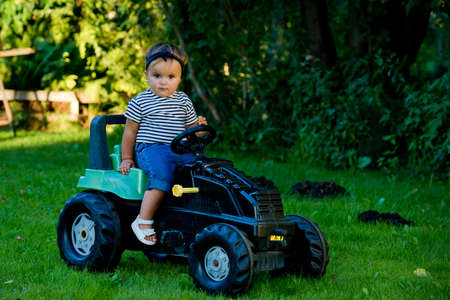 Little girl playing with toy tractor in a garden.の写真素材