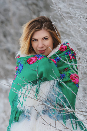 Winter portrait of smiling young woman in snowy forest.