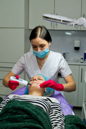 Young woman in beauty salon doing ultrasound peeling and facial cleansing procedure.