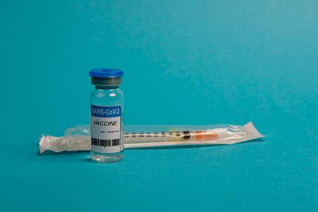 Covid-19 coronavirus vaccine bottle and syringe on blue background. Selective focus.の写真素材