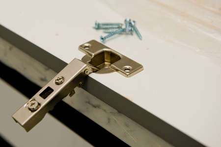 Installation of metal hinges to the chipboard. Selective focus. Close up.の写真素材