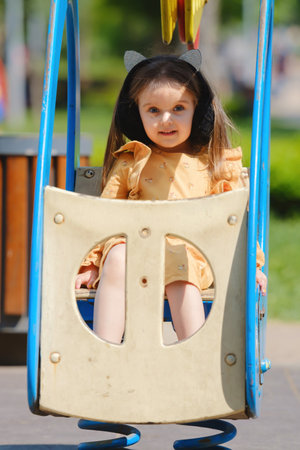 Happy little girl is playing on the playground in the park.の写真素材