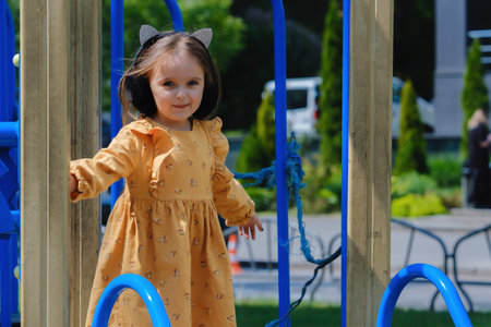 Happy little girl is playing on the playground in the park.