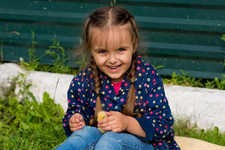 Cute happy little girl with small ducklings in the garden. nature background.の写真素材
