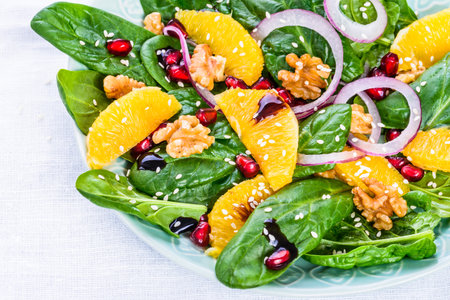 Healthy vitamin salad bowl text space.Salad with spinach leaves and orange, pomegranate and nuts.の写真素材