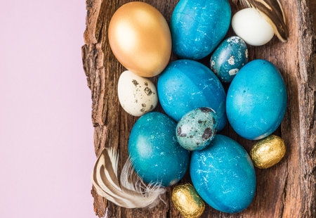 Easter naturally dyed eggs turquoise and gold on light pink background. Easter holiday background text space.の写真素材