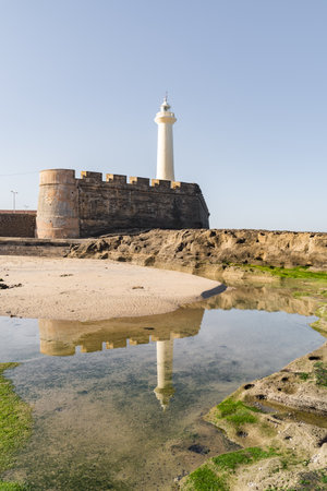 fortress with a lighthouse on the coast of the Atlantic ocean in North Africa against the blue skyの写真素材