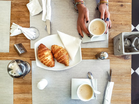 hands Cup of coffee held on the table is a croissant the second Cupの写真素材
