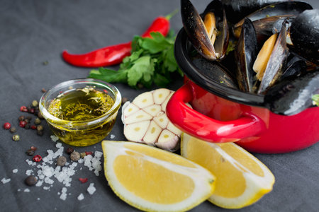 Casserole with mussels, lemons, chili pepper and spices on dark textile backgroundの写真素材