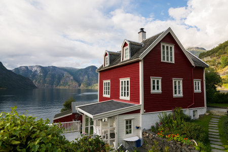 AURLAND, NORWAY - AUGUST 2017: Tradional red wooden house standing on the shore of Aurlandsfjord, Norwayのeditorial素材