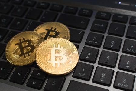 Bitcoin cryptocurrency coins lying on laptop keyboardの写真素材