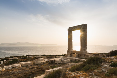 View over ruins of ancient marble doorway monument Portara at sunset in Naxos, Greece.の写真素材