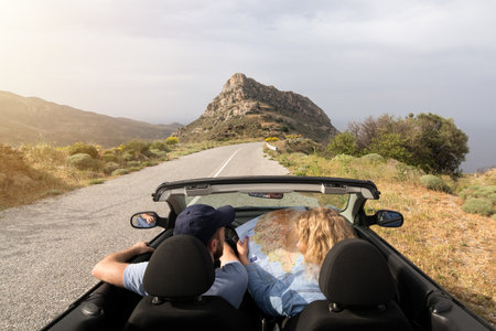 Young couple driving in convertible blue car without roof on mountain road in Naxos island, Greece....